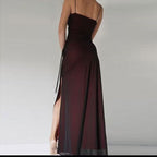 Long burgundy dress with a high slit on a plain background
