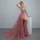 Woman in a pink evening gown with a high slit standing in a bright room.