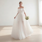 Woman in a white wedding dress holding flowers in a bright room with white curtains.