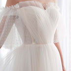 Close-up of a white tulle dress with sheer sleeves on a blurred background